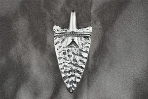 Detail of vintage textured arrowhead pendant with hammer-finish surface and rope detail