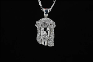 Macro shot of silver hip hop Jesus head pendant with iced-out crystals on black background