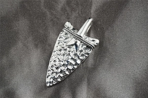 Macro detail of silver arrowhead pendant featuring hammer-patterned texture and rope design