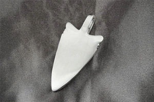 Macro shot of silver arrow pendant with brushed matte finish on dark silk background