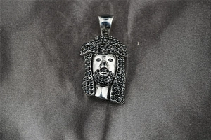Close-up of hip-hop Jesus head pendant with black pave-set stones on silk background