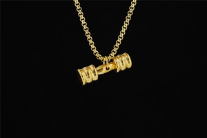 Close-up of polished gold dumbbell pendant with solid link chain for fitness jewelry