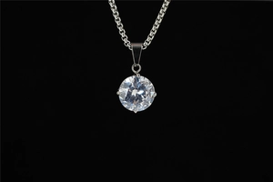 Dettaglio di un ciondolo in moissanite rotonda con montatura a quattro griffe lucida