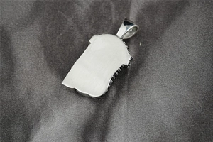 Macro view of hip hop Jesus pendant back featuring brushed silver metal and black stones
