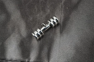 Macro shot of silver dumbbell pendant made of polished stainless steel for fitness jewelry