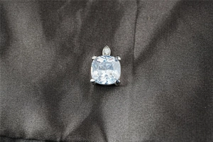 Dettaglio del ciondolo in moissanite taglio cushion con montatura a quattro griffe