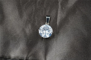 Vista macro di un ciondolo in moissanite con classica incastonatura a quattro griffe in argento