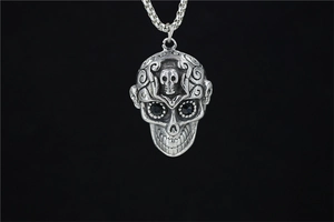 Détail d'un pendentif tête de mort avec yeux en pierres noires et motifs ornés