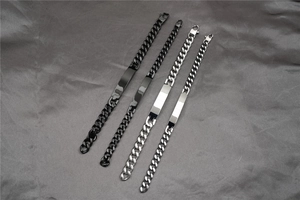 Detailed close-up of cuban link ID bracelets in black and silver finishes on silk fabric