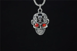 Vue détaillée du pendentif crâne vintage avec yeux en strass rouges sur chaîne acier