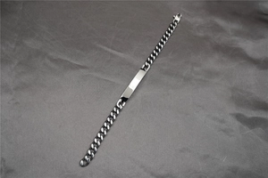 Detail of silver Cuban link bracelet with rectangular polished engraving plate and lobster clasp