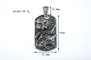Détail d'un pendentif en acier vintage avec relief dragon et tigre et cristaux incrustés