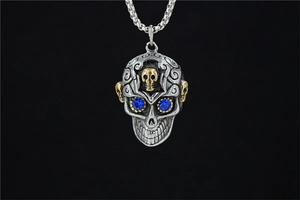 Détail du pendentif crâne gothique avec cristaux bleus et gravure sur chaîne maille miroir