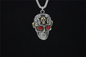 Vue détaillée du pendentif crâne gothique avec yeux en strass rouge et détails dorés