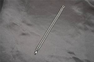 Detailed close-up of a silver Cuban link chain bracelet on a dark silk background
