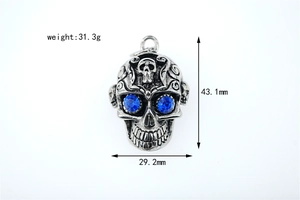 Détail d'un pendentif tête de mort avec gemmes bleues et gravures vintage