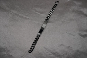 Macro shot of black curb chain ID bracelet showing polished rectangular metal plate