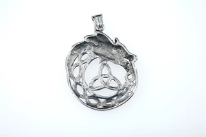 Macro view of Celtic Triquetra knot and dragon relief on silver stainless steel pendant