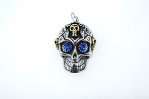 Détail d'un pendentif crâne gothique avec gravures florales et yeux en strass bleus