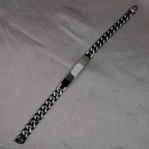 Black and silver Cuban link bracelet with a polished rectangular bar on grey fabric