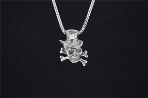 Vue détaillée du pendentif tête de mort avec chapeau sur collier chaîne vintage