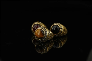 Detail of vintage bronze rings with tiger eye and gemstones on black mirror surface