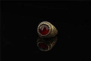 Macro detail of vintage gold ring featuring a deep red gemstone and black rhinestones