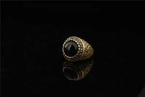 Macro detail of a vintage gold steel ring with black oval stone and intricate carvings