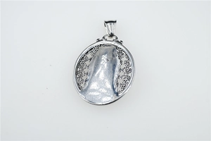Close-up of hollowed-out oval titanium steel pendant featuring Guanyin relief carving