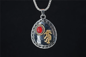 Detail of retro ethnic necklace showing red gemstone inlay and Kokopelli engraving