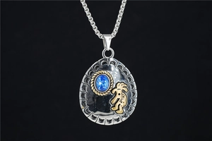 Detailed shot of ethnic silver pendant with blue gemstone and golden Kokopelli totem