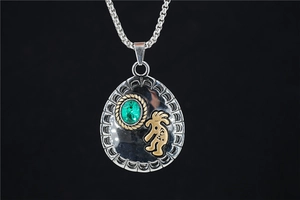 Macro shot of ethnic silver pendant with green gemstone and golden Kokopelli detail