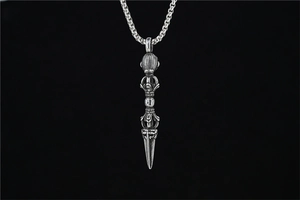 Macro detail of vintage silver vajra pestle pendant with box chain on black background