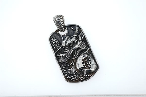 Macro view of vintage relief dragon carving on rectangular stainless steel pendant