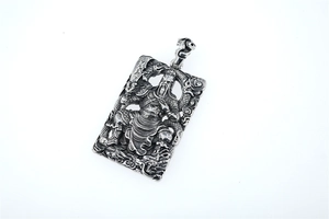 Detail of retro silver Guan Yu pendant with dragon carving and embossed metal texture