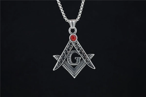 Detailed close-up of a vintage Freemasonry pendant with a red zircon and silver aged finish