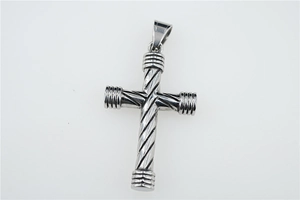 Détail d'un pendentif croix argenté avec texture torsadée et embouts côtelés