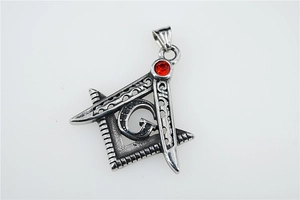 Macro detail of vintage silver Freemason pendant with red zircon and engraved G symbol
