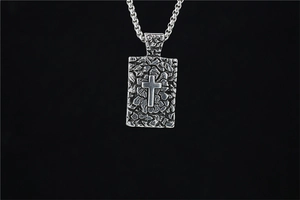 Détail du pendentif croix avec finition martelée sur une chaîne robuste en acier