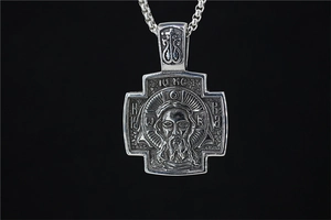 Macro detail of vintage black silver cross pendant with religious icons and thick chain