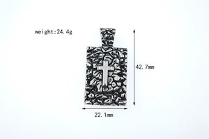 Détail macro du pendentif croix en acier inoxydable avec dimensions et surface texturée