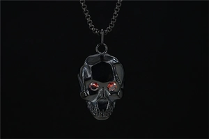Détail macro d'un pendentif crâne gothique noir avec yeux en pierres précieuses rouges