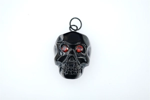 Détail macro du pendentif crâne gothique en métal poli noir avec yeux en zircon rouge