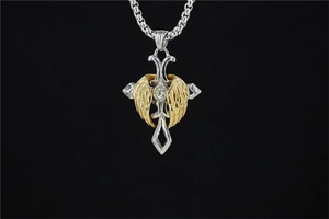 Macro shot of gothic cross necklace with gold feather wings and sparkling center crystal