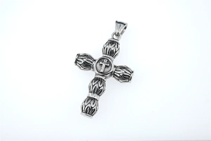 Macro shot of retro stainless steel cross pendant with detailed floral relief and oxidation