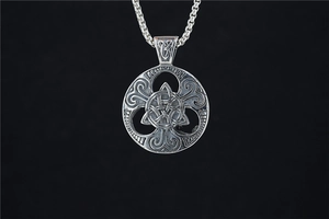 Detail of a silver Celtic knot pendant with hollow vintage patterns on black background