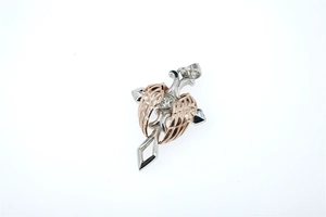 Macro detail of the silver cross pendant with rose gold wings and central gemstone