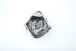 Macro detail of a triangular silver wolf pendant with textured punk engraving