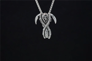 Macro view of gothic reaper pendant with dual scythes and skull in antique silver finish