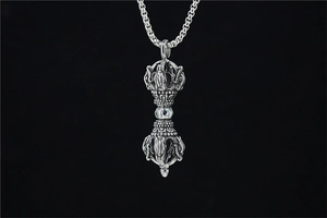 Detailed view of a vintage silver Vajra pestle pendant with intricate religious patterns
